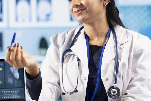 Indian healthcare expert sharing medical expertise with a patient in clinic office, reviewing x ray scans and MRI diagnostics to focus on accurate treatment and recovery. Insurance consultation.